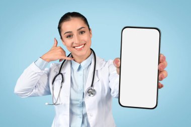 Neşeli kadın doktor akıllı telefon ekranı sergiliyor ve bana el hareketi yapıyor, muhtemelen tele-sağlık hizmetleri için, boş alan, modelleme için.