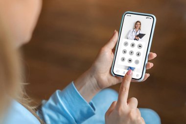 Genç bir kadın sağlık hizmetlerine ve tavsiyelere ulaşmak için evdeki akıllı telefondan tıbbi uygulama kullanıyor. Uygulama menüsünde tanınmayan bir kadın geziniyor. Modern teletıp ve kolajın keyfini çıkarıyor.