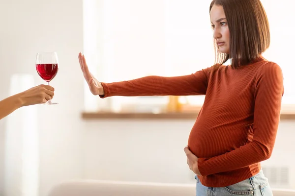 No Alcohol. Determined Pregnant Lady Gesturing Stop To Offered Glass Of Wine Standing At Home Interior, Refusing To Take Alcoholic Drinks During Pregnancy Time, Caring For Unborn Baby