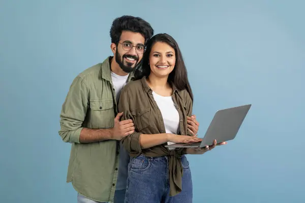 オンライン教育 ショッピングコンセプト ハッピーミレニアルインドカップル一緒にラップトップを使用して 購入またはレッスンやビデオを見る 青い背景に立って スペースをコピー — ストック写真