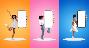 Cool App. Cheerful Multiethnic Females Demonstrating Smartphones With Big Blank Screen While Standing On Platform Against Colorful Backgrounds, Positive Women Recommending Mobile Application, Mockup