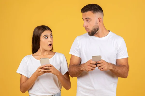 Young Woman Man White Shirts Both Holding Smartphones Surprised Expressions — Stok fotoğraf
