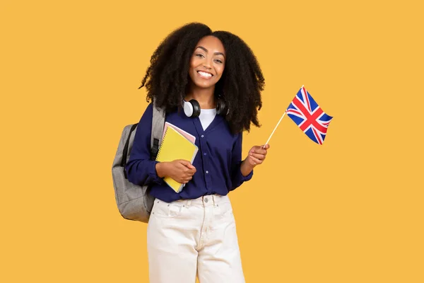 Excited Black Female Student Backpack Copybooks Holds British Flag Smiling — Stockfoto