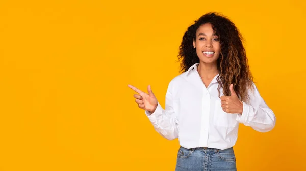 Excited African American Woman Gesturing Thumbs While Pointing Finger Aside — Stockfoto