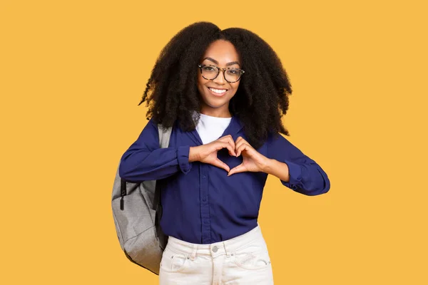 Joyful Black Lady Student Wearing Backpack Forms Heart Shape Hands —  Fotos de Stock