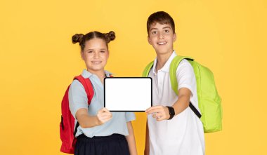 A schoolgirl and schoolboy with backpacks smilingly present a tablet with a white screen, ready for customization, against a yellow background, suggesting interactive learning