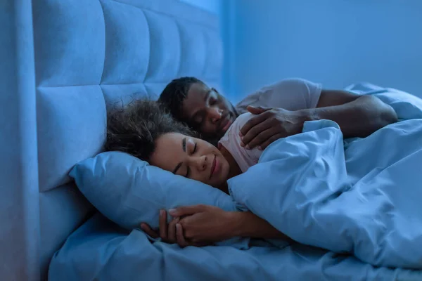 Young African American Couple Sleeping Embracing Blanket Modern Bedroom Night — Stockfoto