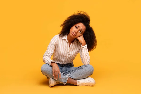 Contemplative Young Black Woman Voluminous Curly Hair Sits Cross Legged — Zdjęcie stockowe