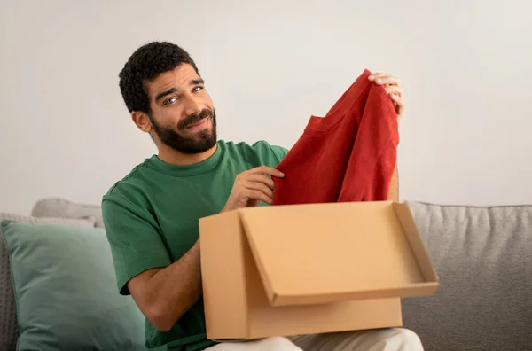 Smiling Middle Eastern Young Man Green Shirt Skeptically Examines Red — Stock Photo, Image