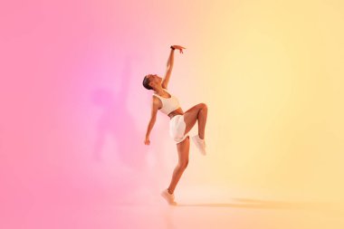 An exuberant latin young dancer in a dynamic pose captures the essence of movement and grace, set against a gradient pink and yellow background. Sport, fitness and weight loss