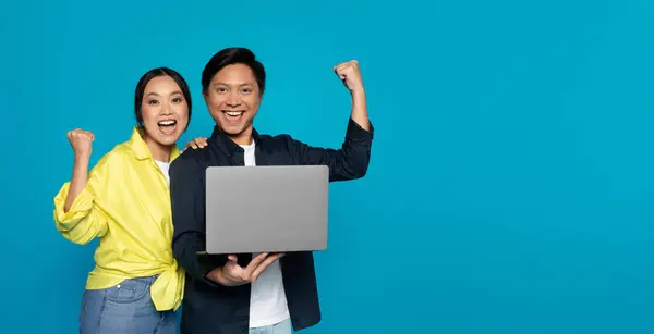 Overjoyed Millennial Asian Couple Triumphantly Raising Fists While Holding Laptop — Stok fotoğraf
