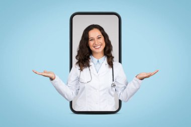 Digital healthcare concept with smiling female doctor displayed inside smartphone frame, hands raised in balancing gesture on blue background