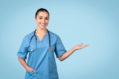Confident and friendly female nurse in blue scrubs presenting with an open hand gesture, ready to display medical information or product