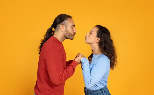 Romantic Millennial Man Woman Holding Hands Kissing Orange Studio Background — Stockfoto
