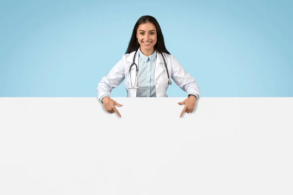 Smiling Female Doctor Pointing Downwards Blank White Banner Text Graphics — Stockfoto
