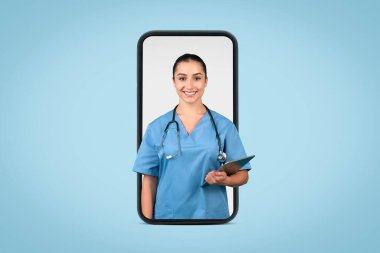 Female doctor in giant phone screen on blue background, holds clipboard and smiles at the camera, representing accessible telemedicine healthcare