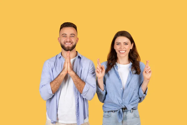 陽気な黄色の背景に対して 希望と楽観主義の両方を示し 祈りの位置と指を持つ手を持つポジティブな若者 — ストック写真