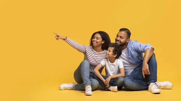 ファミリーオファー 黄色い背景 陽気なアフリカ系アメリカ人の母親 父と男性の子供が広告のための自由な場所を示すコピースペースで幸せな黒人の親と小さな息子 — ストック写真