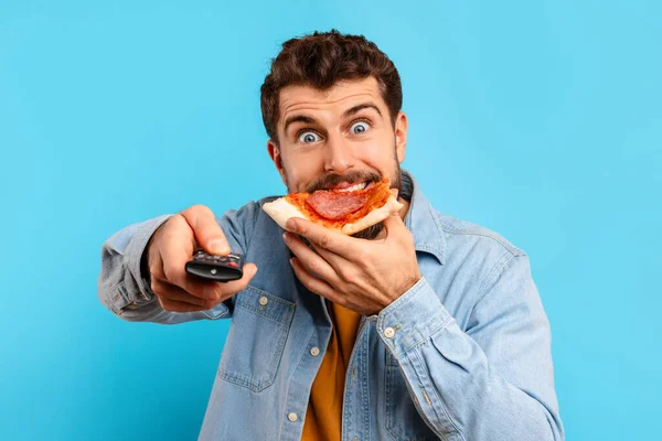 Funny Hungry Millennial Man Eating Pizza Watching Pointing Remote Control — Stock Photo, Image