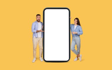 Şaşkın adam ve kendine güvenen kadın aralarında büyük bir akıllı telefon ile iletişim kuruyor. Reklam için mükemmel, parlak sarı arka planda.