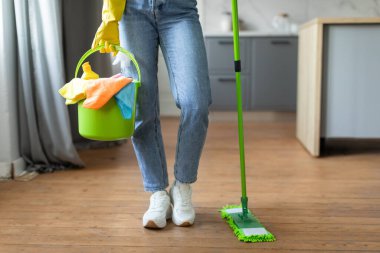 Kotlu ve spor ayakkabılı kadının alt tarafına yakın çekim, temizleme kovasını bez ve paspas ile tutmak, temizlik işleri için hazırlanmış, kırpılmış