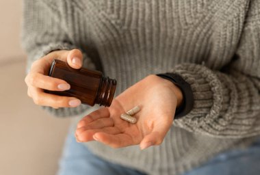 Kadın elinde cam kavanozla haplar, ilave vitamin ve mineraller ile kış mevsiminde kırpılmış. Tanınmayan bayan ağrı kesici al.