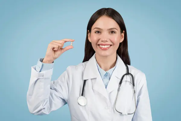 Médica Sorridente Exibindo Pequena Pílula Entre Dedos Representando Assistência Farmacêutica — Fotografia de Stock