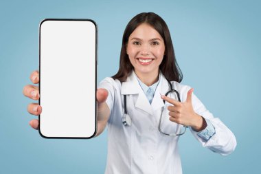 Gülümseyen kadın doktor boş akıllı telefon ekranına işaret ediyor, dijital sağlık uygulamaları ve teletıp, model, mavi arka plan için ideal