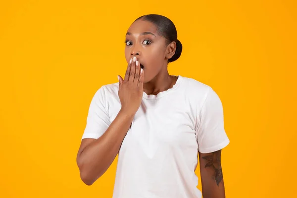 OMG. Portrait Of Shocked African American Woman Covering Mouth With Hand And Looking At Camera, Surprised African American Lady Standing Emotionally Reacting To News On Yellow Backdrop
