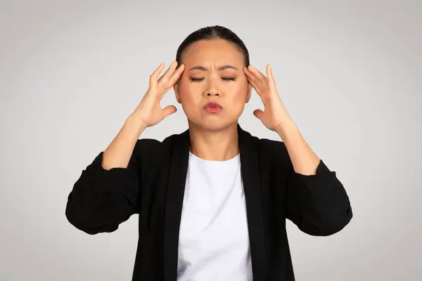ストレスを受けたアジアのビジネスマンは 頭を保持する痛みを伴う表現 頭痛を描写したり プロの職場のシナリオで圧倒的な圧力 灰色の背景に孤立 スタジオ — ストック写真