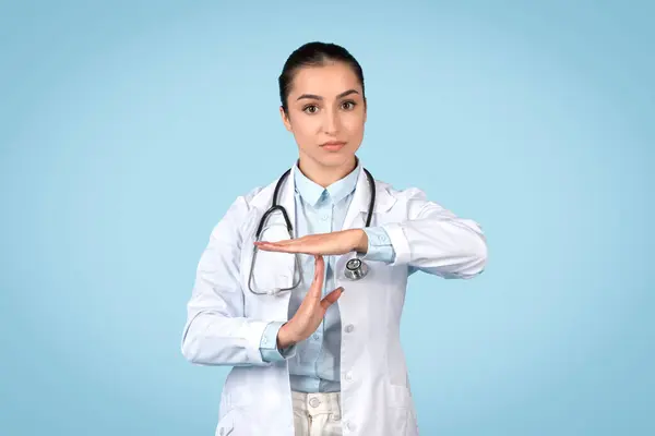 Sebevědomá Doktorka Bílém Kabátě Stetoskopem Odpykává Gesto Rukou Stojí Modrém — Stock fotografie