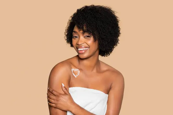 Usmívající Afroameričanka Krémovým Srdcem Nakresleným Rameni Zabalená Bílém Ručníku Ukazující — Stock fotografie