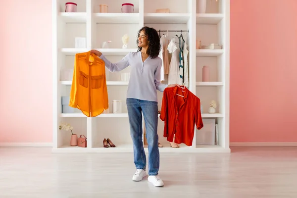 Mujer Pelo Rizado Felizmente Comparando Vibrante Camisa Naranja Con Una — Foto de Stock