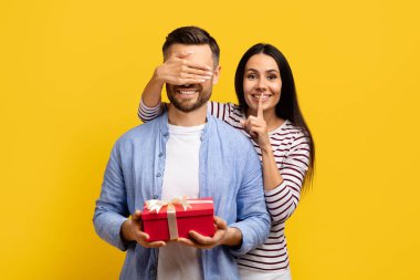 Kocasının gözlerini kapayan ve sürpriz yapan, neşeli, beyaz kadın 