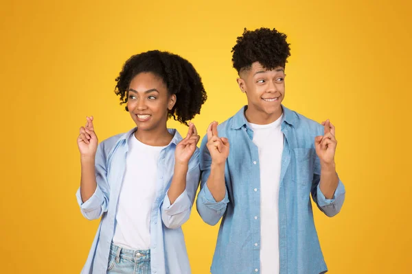 乐观快乐的非洲裔美国青年男女 手指头交叉 表情充满希望 举止随意 站在黄色的背景下 希望好运 — 图库照片
