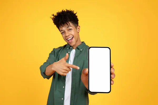 积极的黑人年轻人展示大智能手机与白色空白屏幕模型复制空间的广告 孤立在黄色工作室的背景 移动应用程序 — 图库照片