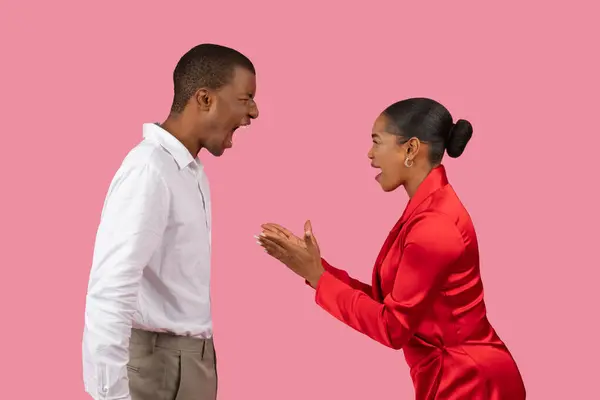 身穿白衬衫的黑人男子和身穿红衣服的妇女在粉红的背景下展开热烈的讨论 带着满腔热情的表情做手势 — 图库照片