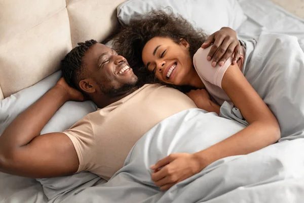 ベッドに横たわる黒人の若い男女を愛し 放射能の幸せを抱きしめ 彼らのカジュアルな抱擁の遺言を彼らのケアフリーで愛情深い関係 寝室で一緒に居心地の良い朝を楽しんで — ストック写真