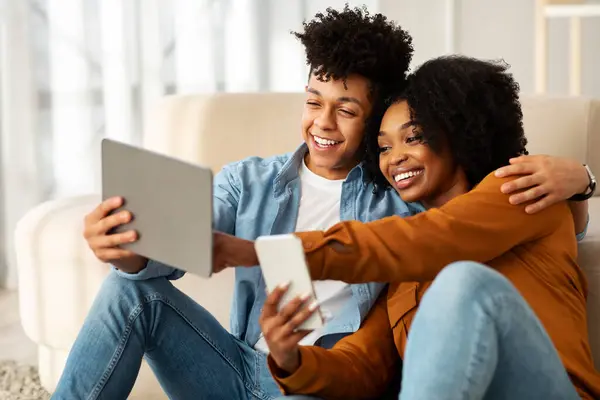 Lächelndes Junges Schwarzes Paar Mit Smartphone Tablet Auf Dem Boden — Stockfoto
