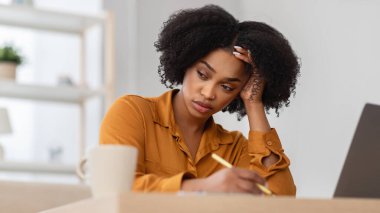 Yorgun, genç, kıvırcık, Afro-Amerikan kadın öğrenci müdürü oturma odasında, panorama 'da bilgisayarla stres yaşıyor. İş, ev işlerindeki sorunlar, teslim tarihi, hata, aşırı çalışma