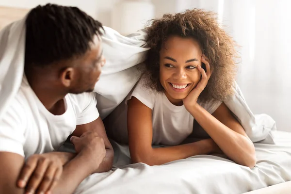 Happy Young Black Lovers Para Flirtuje Łóżku Pod Kocem Uśmiechając — Zdjęcie stockowe