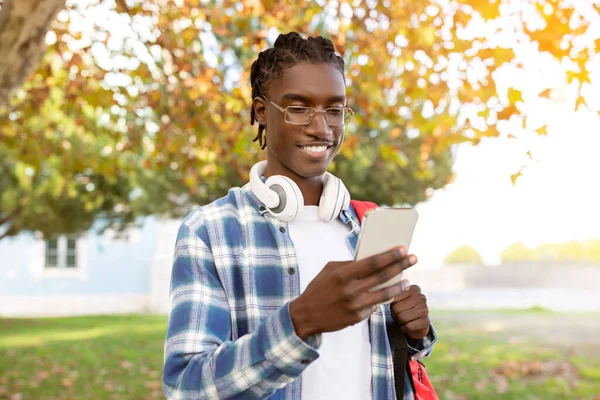 Content Young African American Man Headphones His Neck Checks Smartphone — Stock Photo, Image