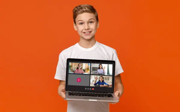 Remote education. Cute boy teenager showing laptop with online lesson screen, posing isolated on orange studio background, kid have video call with classmates and teacher, collage, copy space
