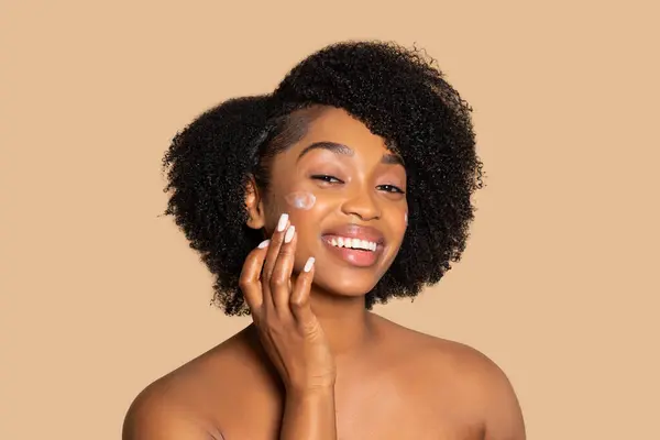Joyful Black Woman Luscious Curly Hair Gently Applies Moisturizing Cream — Stock Photo, Image