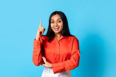 Eureka, ilham. Hevesli genç Hintli bayan, yaratıcı bir fikre sahip olduğuna işaret ediyor. Mavi stüdyo arkaplanı üzerinden kameraya gülümsüyor. Yaratıcılık ve harika çözüm kavramı