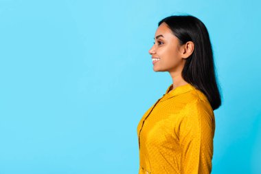 Mavi Stüdyo 'nun arka planında boş alana bakan gülümseyen Hintli genç bayanın portresi, reklam indirimi teklifi. Çekici Orta Doğulu Kadının Profil Fotoğrafı