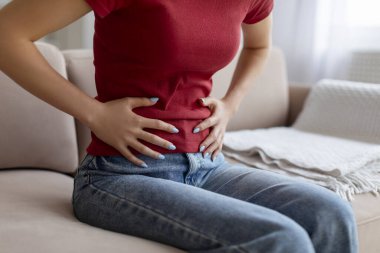 Tanımlanamayan bir kadın evde karın ağrısı çekiyor. Genç bir kadın oturma odasında koltukta otururken karnına dokunuyor. Sindirim problemleri yaşıyor.