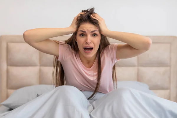 Yatakta Oturan Ürkmüş Genç Bir Kadın Elleri Saçlarını Tutuyor Ağzı — Stok fotoğraf