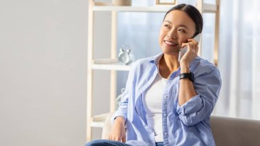 Mutlu Asyalı kadın evinde kanepede oturuyor, arkadaşıyla telefon konuşmasının tadını çıkarıyor, boş fotokopi odasına bakıyor ve gülümsüyor. Cep telefonu operatörü, iletişim konsepti