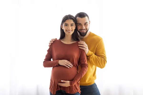 Retrato Joven Embarazada Esposo Abrazando Cerca Ventana Casa Cónyuges Caucásicos —  Fotos de Stock